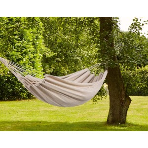 Beżowy hamak zawieszony między dwoma drzewami w ogrodzie. Czysty relaks z odpowiednią huśtawką ogrodową.