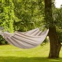Beżowy hamak zawieszony między dwoma drzewami w ogrodzie. Czysty relaks z odpowiednią huśtawką ogrodową.