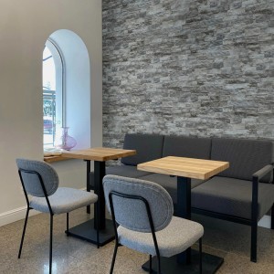 Szara okładzina kamienna na ścianie we wnętrzu, połączona z nowoczesnymi meblami.