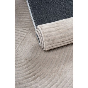 Beżowy dywan z krótkim włosiem, częściowo zwinięty, ze wzorem.