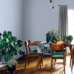 Pokój dzienny z kolorowo pomalowaną ścianą (t.b.t.) i drewnianym stołem z dekoracją.