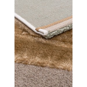 Zbliżenie beżowego dywanu shaggy t.b.t, pokazujące teksturę i spód.