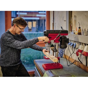 Wiertarka stołowa Einhell TC-BD 450 podczas wiercenia w drewnie, czerwono-czarna.