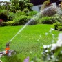 Zraszacz turbinowy Gardena Comfort na sankach nawadnia trawnik w ogrodzie.