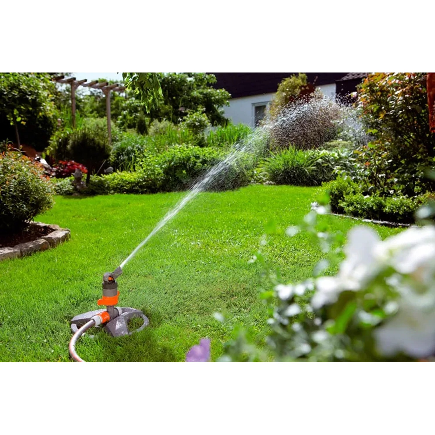 Zraszacz turbinowy Gardena Comfort na sankach nawadnia trawnik w ogrodzie.