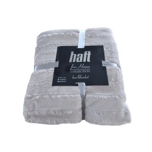 Beżowy koc t.b.t. z frędzlami, złożony i przewiązany wstążką.