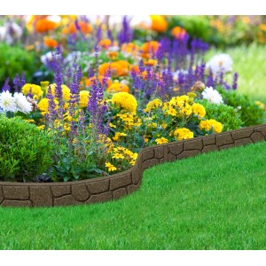 Brązowe obrzeże rabatowe t.b.t. imitujące kamień, użyte w kwitnącym ogrodzie.