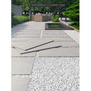 Szare płytki podłogowe t.b.t. na zewnątrz z białymi kamykami dekoracyjnymi.