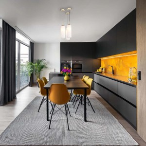 Nowoczesna kuchnia z lampami wiszącymi t.b.t. nad stołem jadalnym z żółtymi krzesłami.