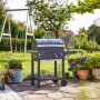 Grill węglowy Jamestown Jaxon w ogrodzie z rusztem i kołami.