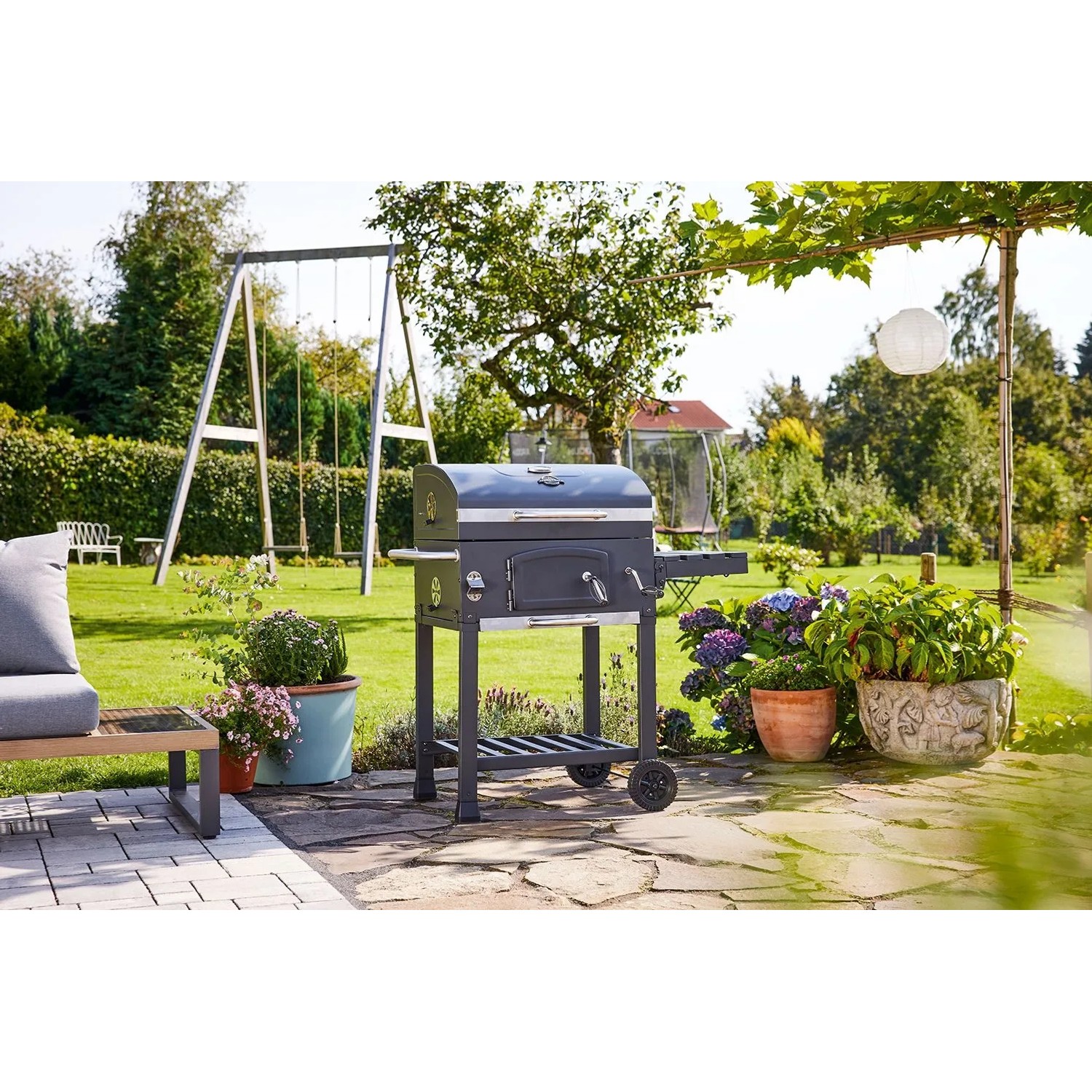 Grill węglowy Jamestown Jaxon w ogrodzie z rusztem i kołami.