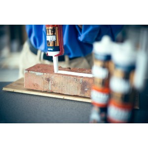 Nakładanie kleju montażowego na cegłę. Klej z kartusza.