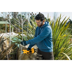 Mężczyzna przycina gałęzie akumulatorowymi nożycami Stiga SC 100 w ogrodzie.