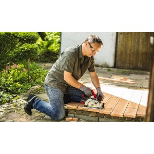 Mężczyzna piłuje drewno akumulatorową pilarką tarczową Einhell Power X-Change TE-CS 18/150 Li Solo w ogrodzie.