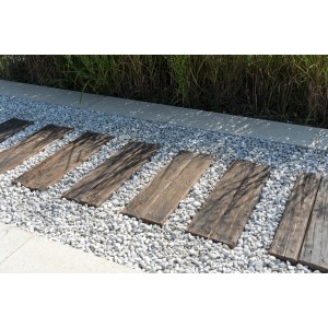 Drewniane deski jako ścieżka ogrodowa między białymi ozdobnymi kamykami. Płyty tarasowe i chodnikowe.