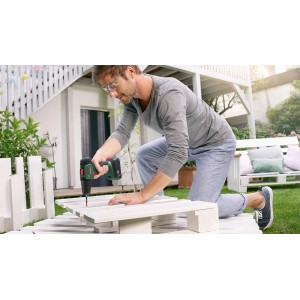 Mężczyzna używa wkrętarki akumulatorowej do projektu DIY w ogrodzie. Wkrętarki akumulatorowe dla majsterkowiczów w OBI.