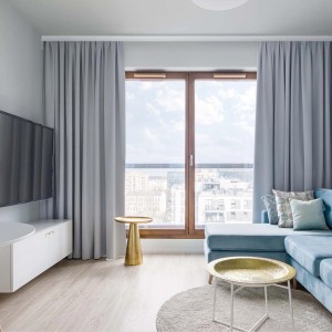Salon z szarymi zasłonami na białym karniszu.