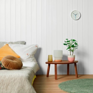 Aranżacja ściany z białą emalią, łóżko, stół z lampą i rośliną w pokoju.