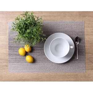 Dekoracja stołu z szarą podkładką t.b.t., naczyniami, rośliną i cytrynami na drewnianym stole.