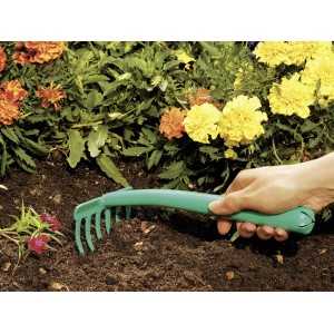 Zielone grabie ręczne LUX z 6 zębami używane w grządce.