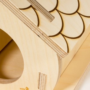 Zbliżenie na jasny, nieobrobiony drewniany karmnik dla ptaków ze wzorem gontu.