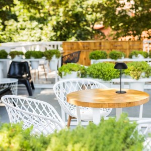 Czarna lampa stołowa t.b.t. na drewnianym stole na zewnątrz.