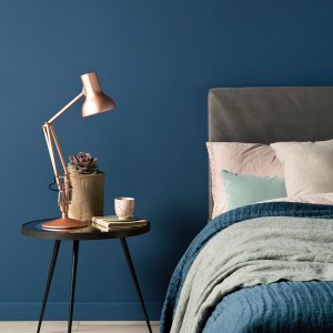 Sypialnia z niebieską farbą na ścianie. Kolorowa farba do ścian dla przytulnej atmosfery.