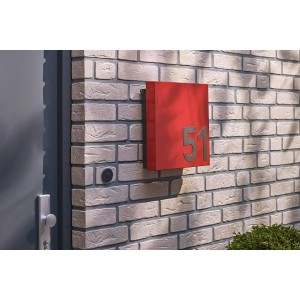 Czerwona skrzynka pocztowa z numerem domu 51 na ceglanej ścianie.