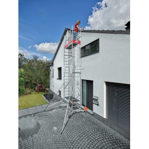 Aluminiowe rusztowanie Krause Monto ClimTec z drugim przedłużeniem przed ścianą domu. Osoba na górnej platformie.