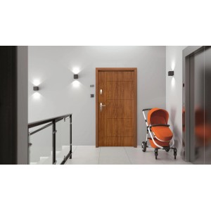 Nowoczesne drewniane drzwi zewnętrzne z okuciami zabezpieczającymi w korytarzu.