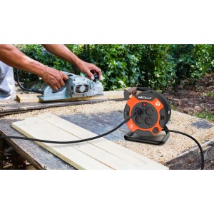 Pomarańczowy przedłużacz bębnowy z wtyczką używany do strugania drewna.