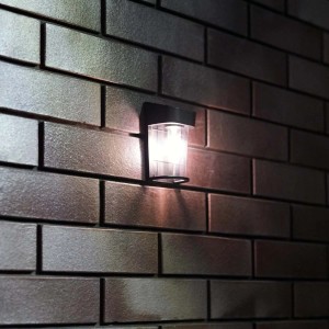 Oświetlona solarna lampa ścienna na ceglanej ścianie.