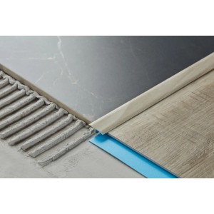 Zbliżenie: Profil do płytek t.b.t., beżowy, ułożony między dwiema płytkami.