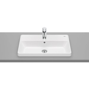 Prostokątna, biała umywalka nablatowa z baterią na szarej powierzchni.