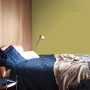 Sypialnia z żółto-zieloną farbą na ścianie. Kolorowe farby do ścian marki t.b.t.