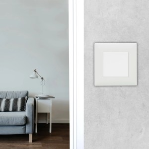 Kwadratowy, biały włącznik t.b.t. na szarej ścianie w salonie.