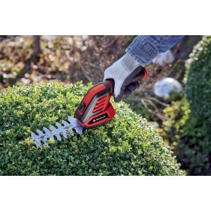 Akumulatorowe nożyce do trawy i krzewów podczas przycinania żywopłotu.