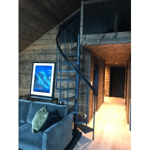 Czarne schody spiralne w nowoczesnym salonie z boazerią. Schody wewnętrzne.