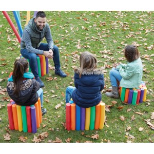 Ludzie siedzą na stołkach z kolorowych makaronów do pływania Comfy w ogrodzie.