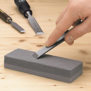 Osełka LUX Classic z dłutem i ręką na drewnianym tle.