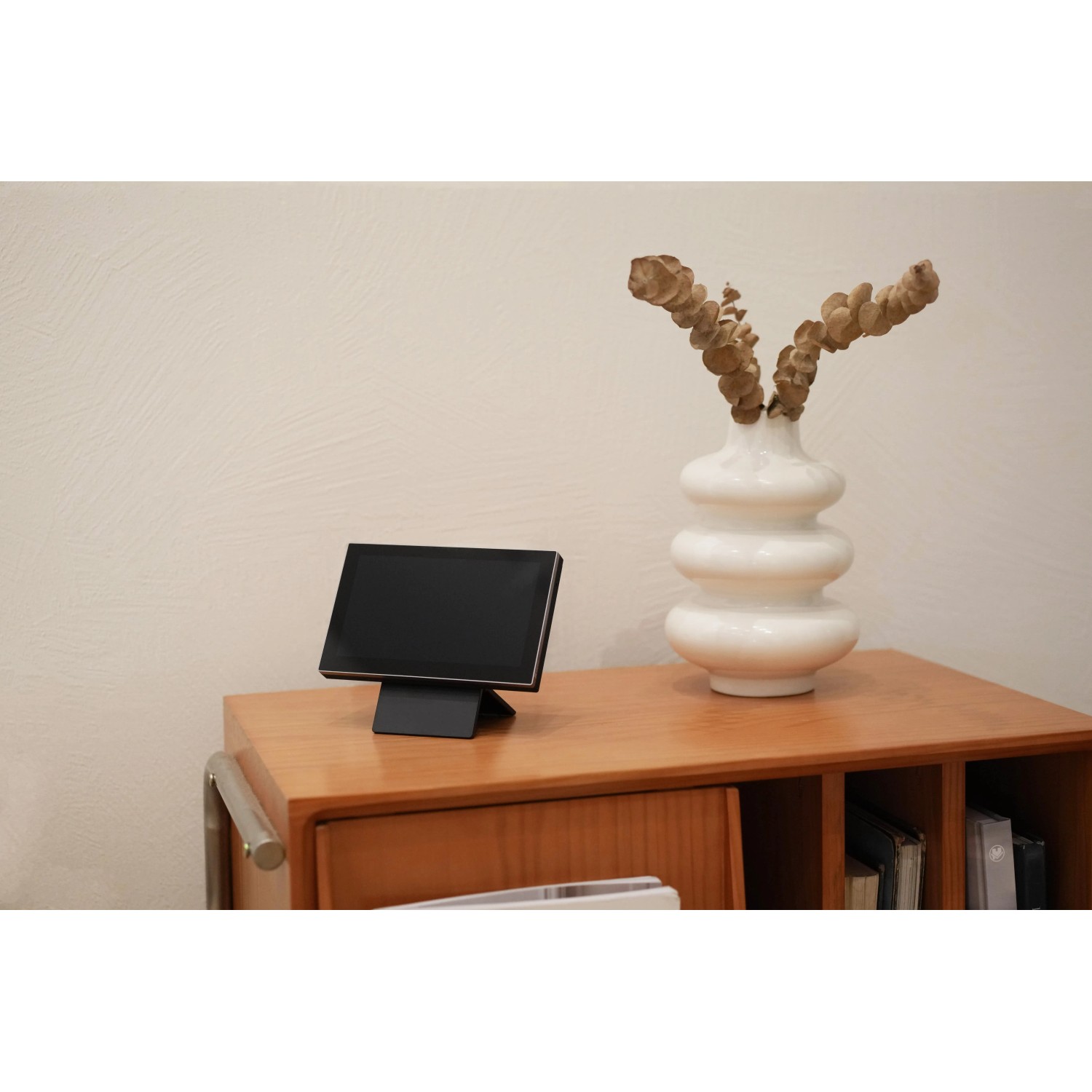 Monitor Ezviz z baterią (17,78 cm) do monitoringu kamer, stojący na drewnianej szafce.