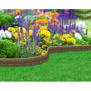 Brązowe obrzeże ogrodowe imitujące cegłę jako obramowanie rabat kwiatowych i trawnika.