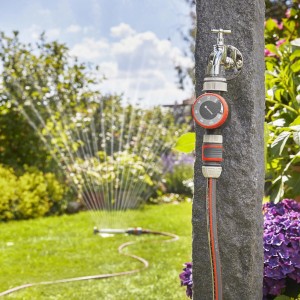 Timer nawadniania Gardena na kranie ze zraszaczem w ogrodzie.