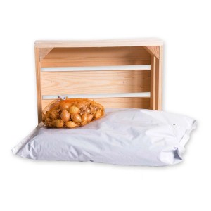 Nasiona t.b.t. w siatkowym worku przed drewnianą skrzynką i białym workiem.