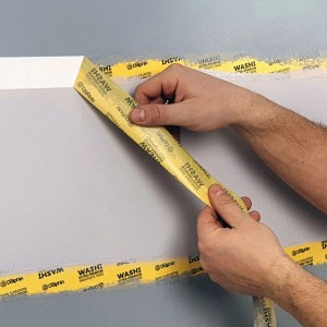 Żółta taśma malarska t.b.t. naklejana na ścianę.