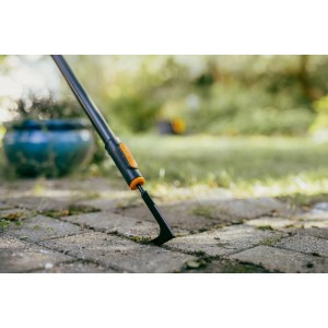 Skrobak do fug Fiskars OneClick w akcji: Usuwanie chwastów spomiędzy kostki brukowej.
