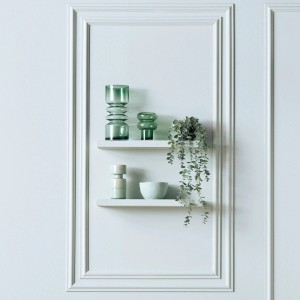 Dekoracyjne szklane wazony i miska w odcieniach zieleni na białych półkach ściennych.