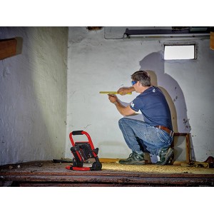 Lampa akumulatorowa w użyciu: Mężczyzna mierzy ścianę z czerwoną lampą t.b.t. na pierwszym planie.