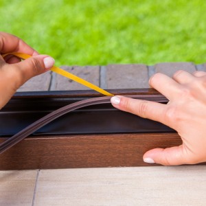 Montaż brązowej uszczelki okiennej (t.b.t.) do ramy okiennej.