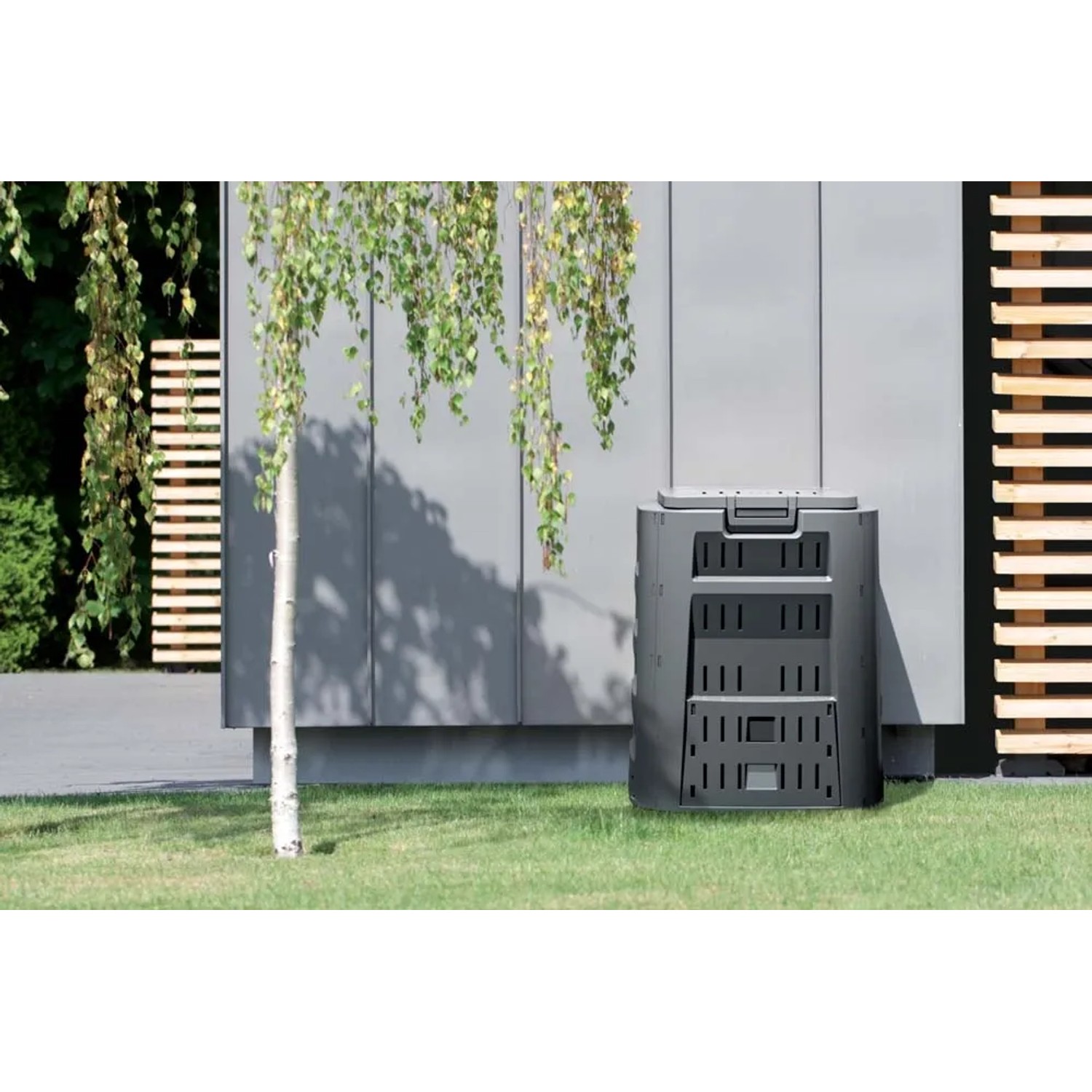 Czarny kompostownik Compogreen 210 l do recyklingu odpadów ogrodowych na zewnątrz.